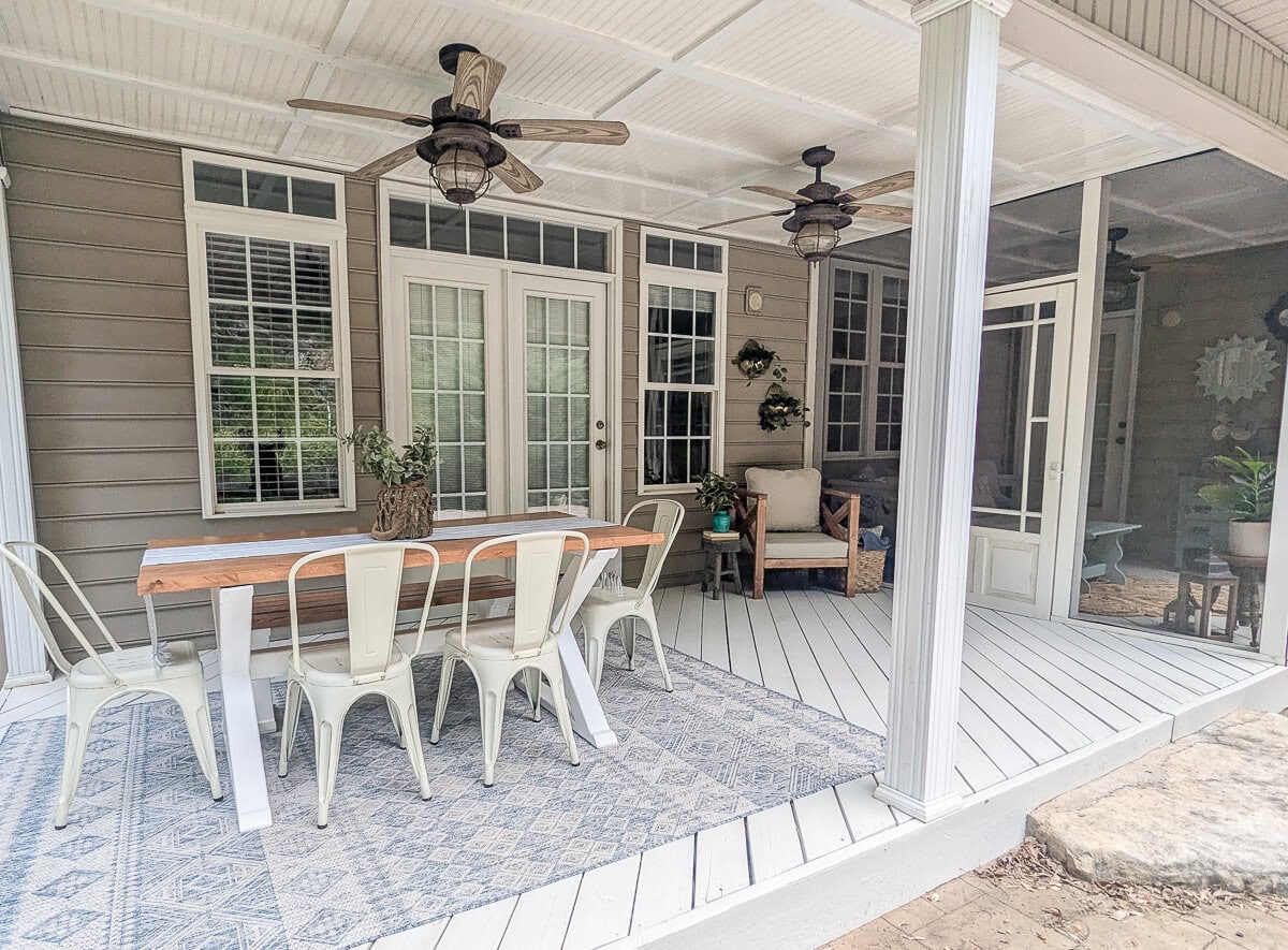 back porch with light painted floor, wooden dining table and chairs.