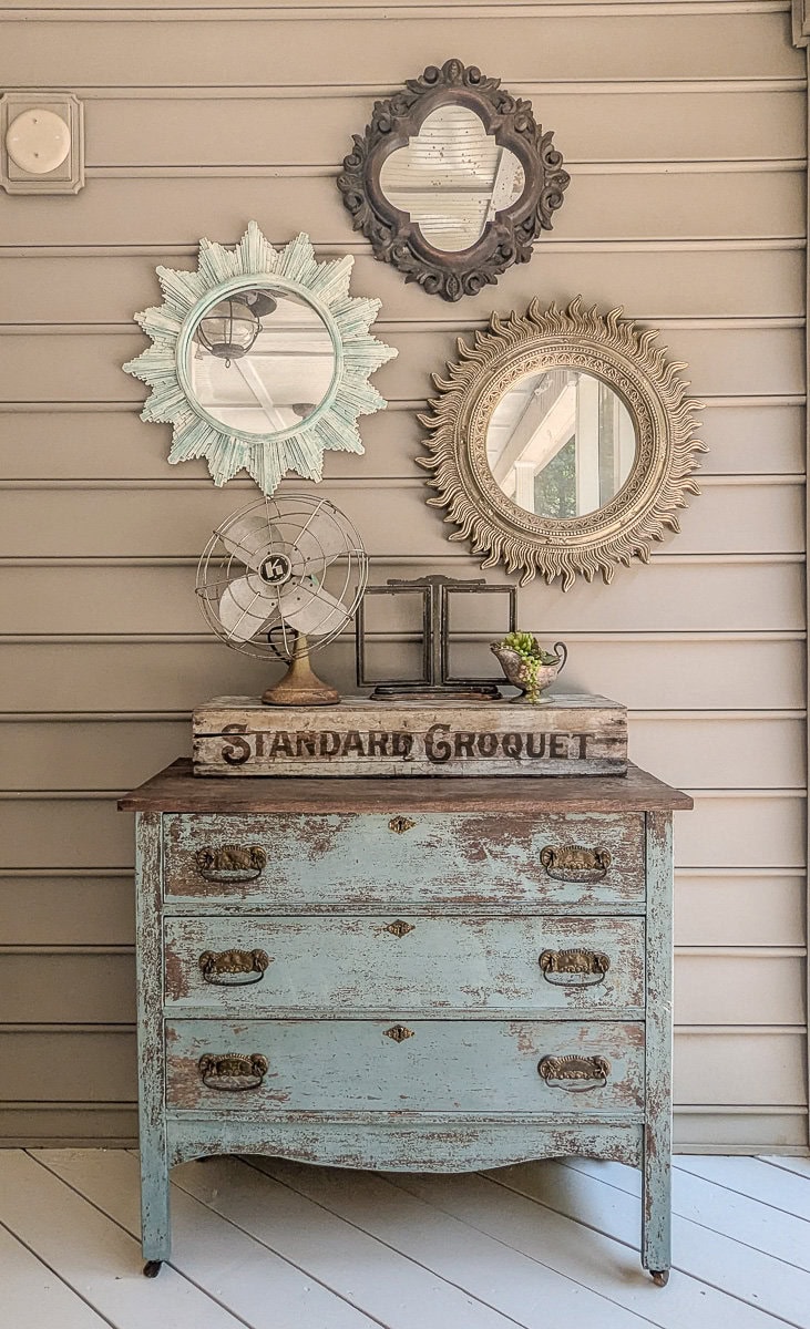 chippy farmhouse dresser and vintage mirrors on porch.