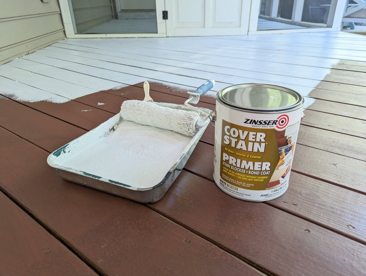 can of oil-based primer and paint roller on half-painted porch floor.