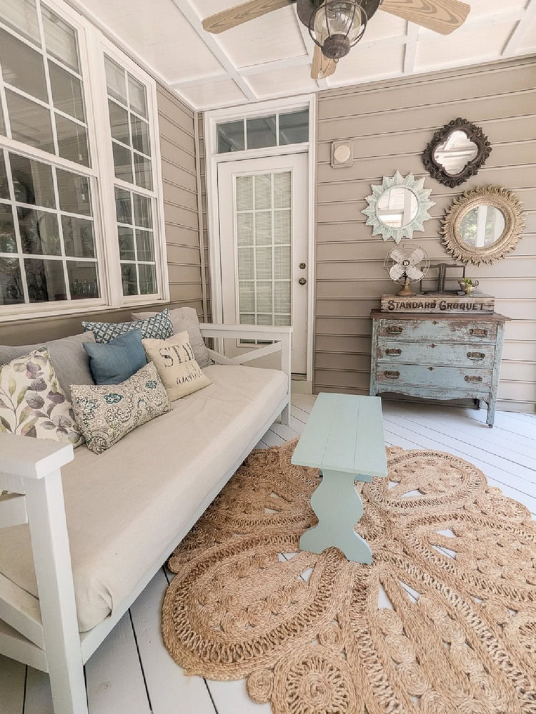 screened in porch with daybed seating and antique dresser.